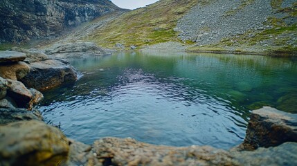 Serene Mountain Lake with Rocky Shoreline and Rippled Water Reflections in a Valley