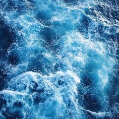 Fototapeta premium Deep blue ocean water with white foam and turbulent waves creating an abstract pattern