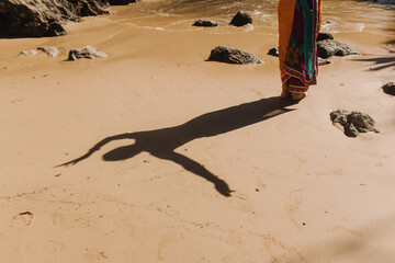 Shadow of a dancing Indian woman in traditional saree clothes on the ocean background. Indian festival costume. Concept of solo tourism and travel to India