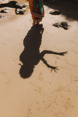 Shadow of a dancing Indian woman in traditional saree clothes on the ocean background. Indian festival costume. Concept of solo tourism and travel to India