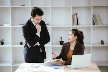 A team of business professionals work together in an office to analyze financial reports, sales strategies, and market statistics using laptops, documents, and graphs.