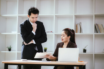 A team of business professionals work together in an office to analyze financial reports, sales strategies, and market statistics using laptops, documents, and graphs.