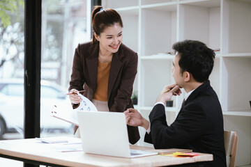 A team of business professionals work together in an office to analyze financial reports, sales strategies, and market statistics using laptops, documents, and graphs.