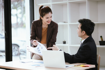A team of business professionals work together in an office to analyze financial reports, sales strategies, and market statistics using laptops, documents, and graphs.