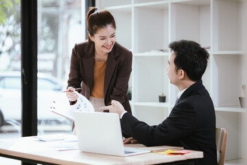 A team of business professionals work together in an office to analyze financial reports, sales strategies, and market statistics using laptops, documents, and graphs.