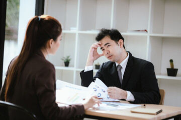 A team of business professionals work together in an office to analyze financial reports, sales strategies, and market statistics using laptops, documents, and graphs.