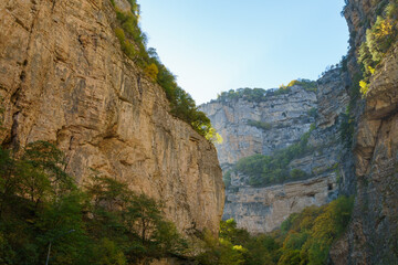 Stunning canyon with steep, rugged cliffs covered in greenery, showcasing majestic beauty of nature under clear blue sky. Kabardino-Balkaria, Russia. Chegem Gorge 2024