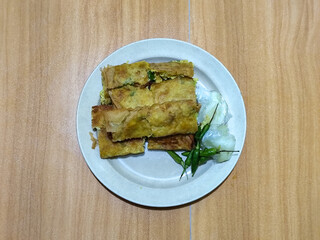 Egg martabak. Egg martabak is a traditional Indonesian food that tastes savory and delicious, served on a plate with pickles and chili.
