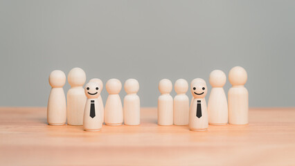 Wooden doll representing individuality and leadership. Two business smiling figures with ties stand...