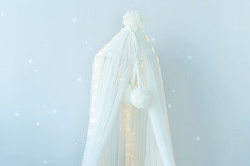Hanging White textile canopy in cozy children bedroom. Stylish scandinavian interior design of newborn room with Baby cot with canopy. Decor child room with furniture. 