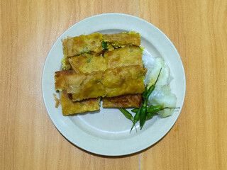 Egg martabak. Egg martabak is a traditional Indonesian food that tastes savory and delicious, served on a plate with pickles and chili.