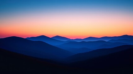 Fototapeta premium Serene landscape photography showing silhouettes of mountains against a vibrant sunset. Pink, orange, and blue hues dominate the sky, creating a