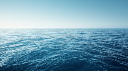Obraz premium Vast expanse of a calm, blue ocean under a clear, light blue sky. The water is subtly textured with small waves, creating a peaceful and serene