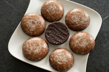 Chocolate coated ginger bread, on a white plate on dark background.. Close up.