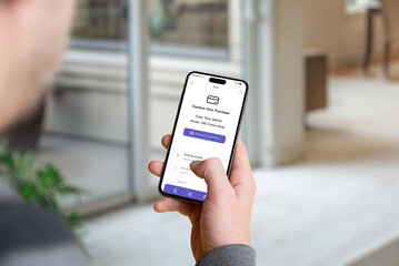 Man holding a smartphone with a banking app confirmation screen showing the purchase amount and an 'Approve Payment' button