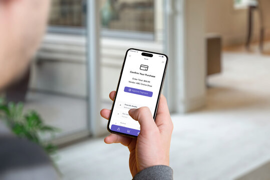 Man holding a smartphone with a banking app confirmation screen showing the purchase amount and an 'Approve Payment' button