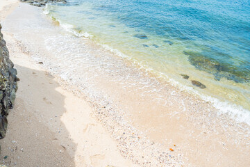 Soft blue ocean wave on clean sandy beach with rocks and splashing waves,Summer vibe on holiday vacation.