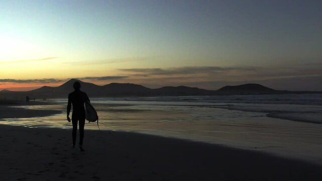 Strand mit Surfer in der Abendsonne bei stimmungsvollem Sonnenuntergang, Meer, Wellenreiter, Urlaub, Idylle, Lanzarote, Kanaren, K&uuml;ste, Landschaft, Bergsilhouetten 