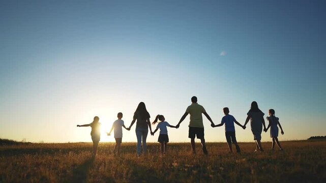 big family. huge community family holding hands walking in the park at sunset. happy family kid dream concept. big family community walking with children in sunlight the park. friendly people walking