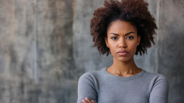 Confident African American Woman with Arms Crossed Displaying Skepticism Against Textured Gray Background