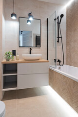Modern interior of bathroom with ceramic bathroom sink with tap , bath with glass, tile on the wall and mirror. Luxurious hygiene room in industrial style with shower and wash basin. Vertical.