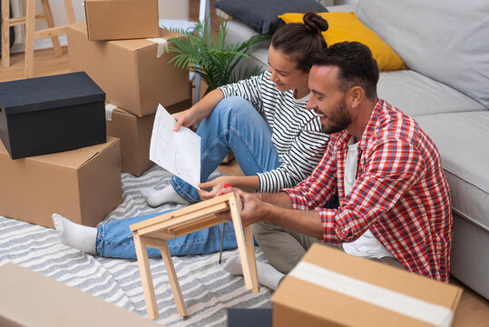 Couple DIY: Happy pair in their new home, assembles modern wooden shelf furniture, surrounded by boxes, enhancing home decor during the move