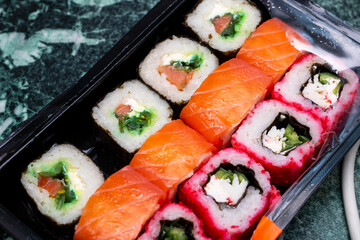 A plastic container that is filled with various types of sushi