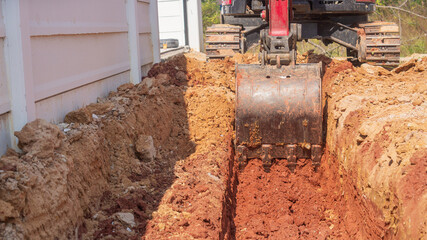 Drainage construction A trench in a construction site where an excavator is used to work.