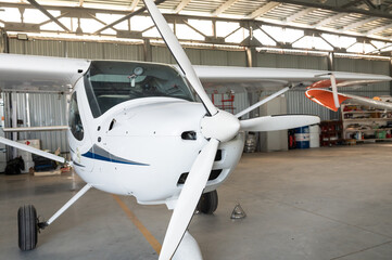 Small white aircraft parked in a hangar