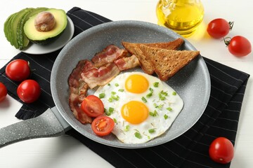 Tasty fried eggs with bacon and toasts served on white wooden table, closeup