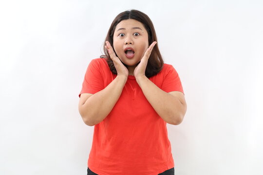 Cheerful asian woman look with surprised face at camera, react to awesome good news, smiling and cheering, standing against white background