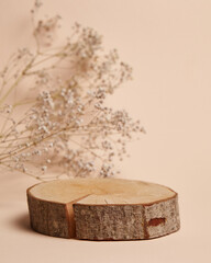 Natural wooden log slice pedestal with visible tree rings and bark, accompanied by delicate dried flowers on a neutral beige background. Ideal for product display, branding, and organic presentations