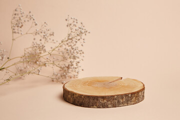 Rustic wooden log slice pedestal with visible tree rings and bark, accompanied by delicate dried flowers on a neutral beige background. Ideal for product display, branding, and presentations