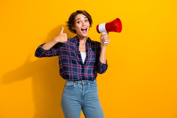 Portrait of optimistic good mood girl wear checkered shirt holding loudspeaker showing thumb up...