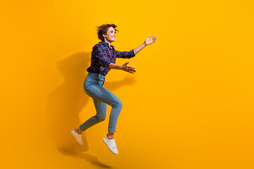 Obraz premium Full length photo of adorable woman dressed plaid shirt jeans fly catching product from empty space isolated on yellow color background