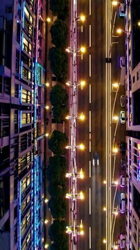 A vertical perspective captures streetlight poles aligned along a bustling avenue, emphasizing vibrant neon highlights. The scene's structured, orderly rhythm, evoking urban energy and precision.
