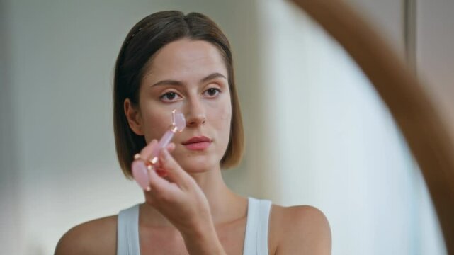 Lady massaging face roller in bathroom home closeup. Woman using quarts massager
