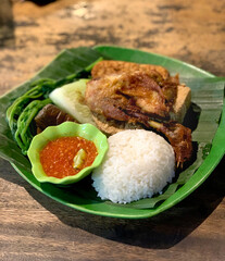 Fried chicken with fermented soy, rice, and cucumber dressing, with typical Indonesian traditional chili onion. Traditional Indonesian food.
