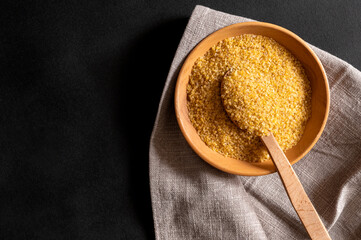 Wheat bulgur in a wooden plate on the table. Top view