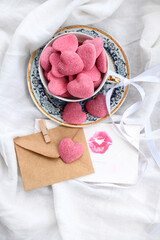Cup with pink gummy hearts, envelope, and love letter on a white background. Composition for Valentine's Day