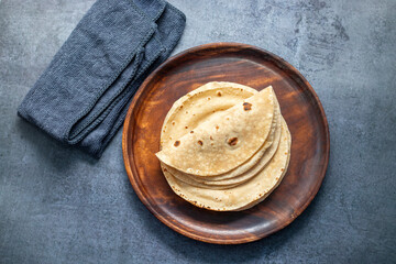 Roti is a soft, round flatbread made from whole wheat flour, commonly eaten in South Asian cuisine with various dishes.