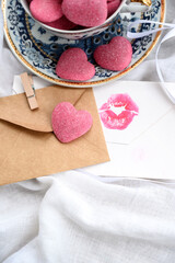 Cup with pink gummy hearts, envelope, and love letter on a white background. Composition for Valentine's Day