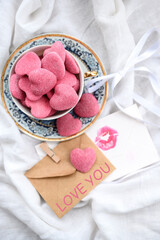 Cup with pink gummy hearts, envelope, and love letter on a white background with love inscription. Composition for Valentine's Day