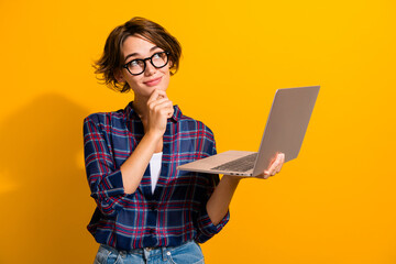 Portrait of pensive smart girl wear checkered shirt in glasses hold laptop look at offer empty...