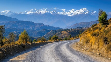 A small mountain road with a clear view of snow-capped peaks in the distance. 
