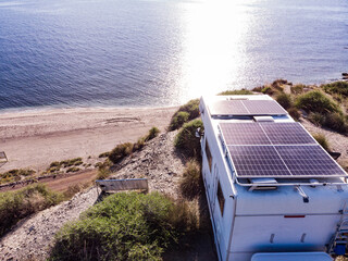 Obraz premium Caravan with solar panels on roof camp on sea, Spain. Aerial view.