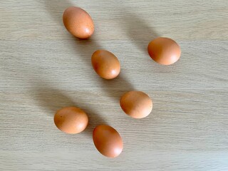 Many brown eggs scattered on a light wooden surface. Perfect for Easter, food-related designs, spring celebrations, and themes of renewal, tradition, or festive gatherings.