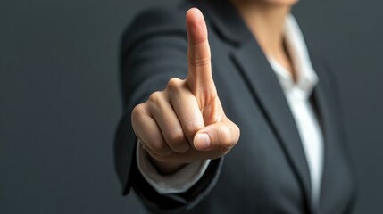 Business woman in formal attire confidently gesturing with index finger raised in sign of excellence against a smooth grey background
