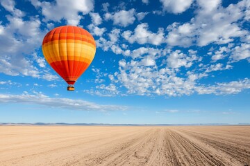 Fototapeta premium Colorful hot air balloon soaring over a vast desert landscape under a bright blue sky with clouds