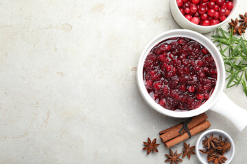Tasty cranberry sauce in gravy boat, honey, spices and berries on light table, flat lay. Space for text